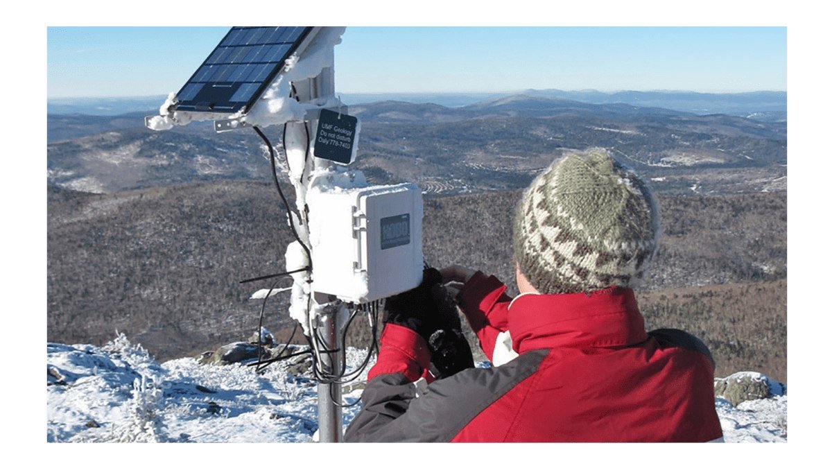 Technician installing a HOBO weather station on a mountain summit